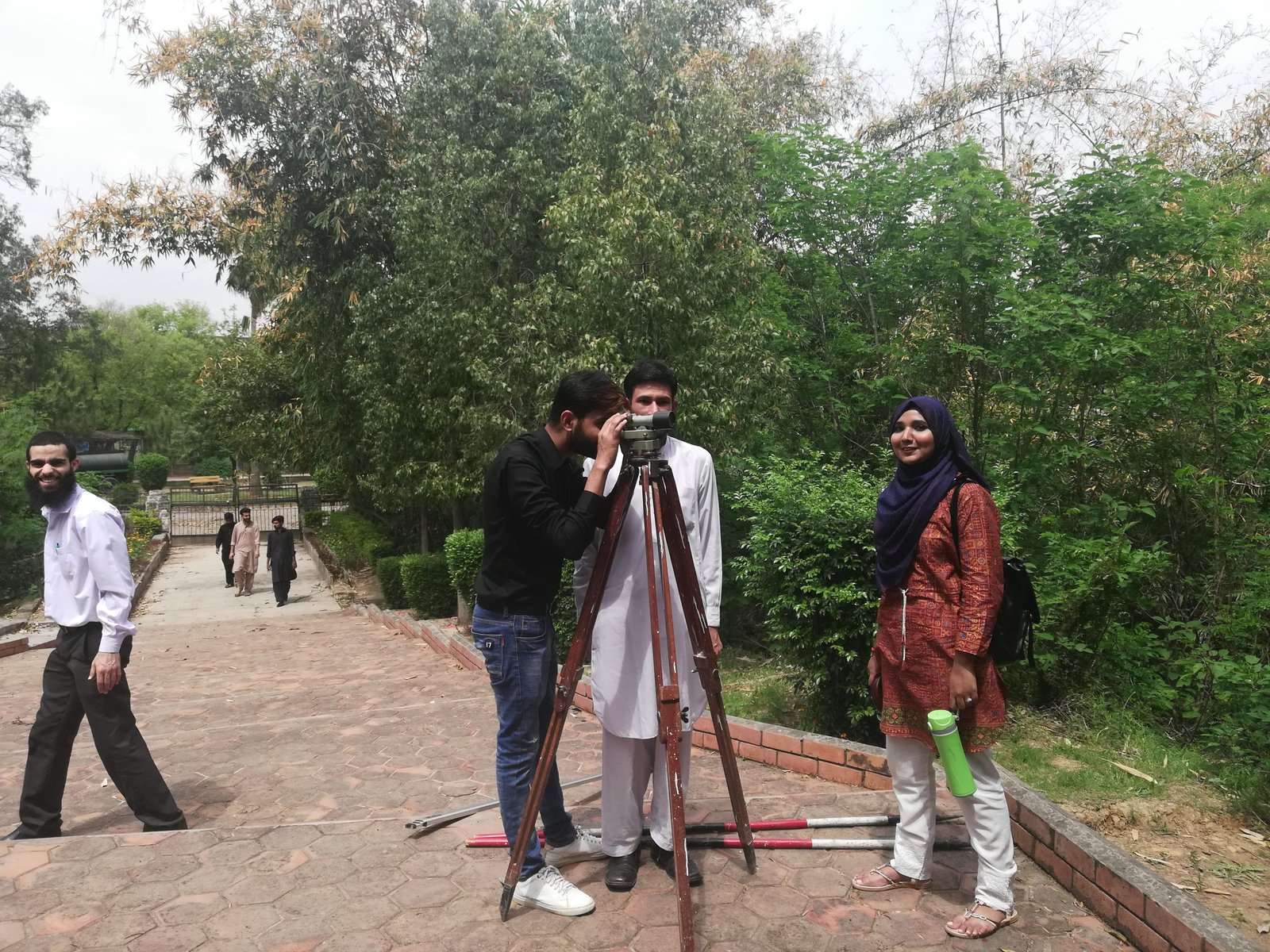 Students taking readings with a theodolite during a field practical survey